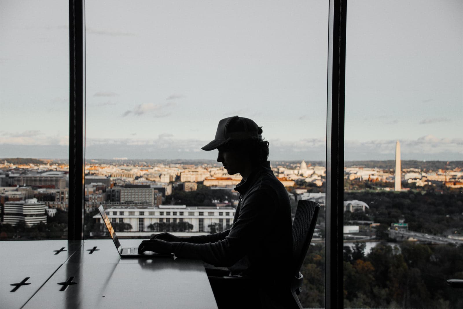 Fritz working on a laptop by a window over the city